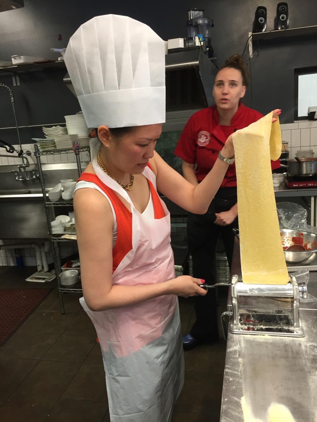 Rina Kim pulling a sheet of pasta from a pasta maker