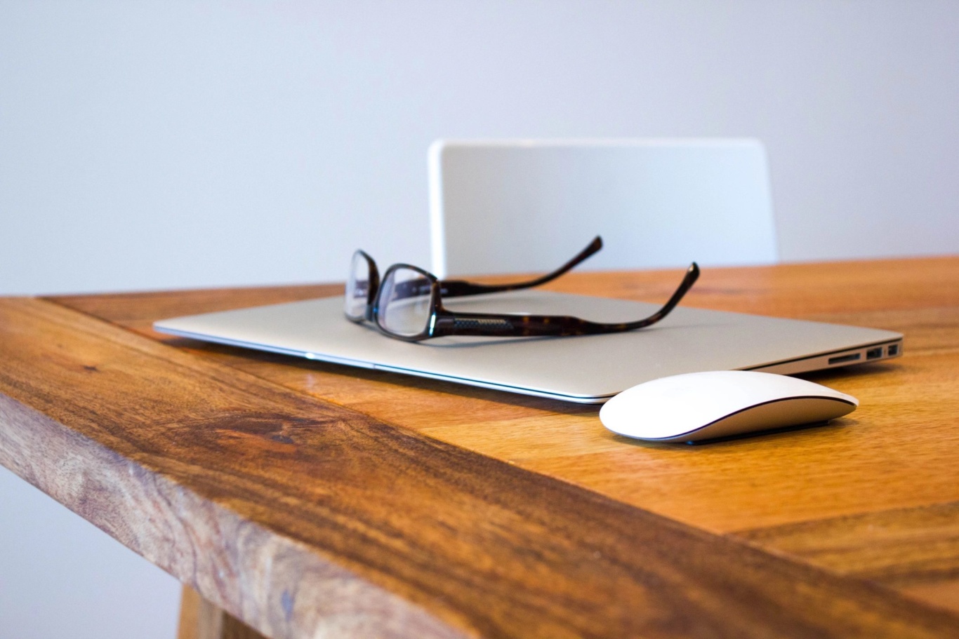 wood desk with laptop and glasses